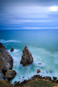 Rocks on sea shore against sky