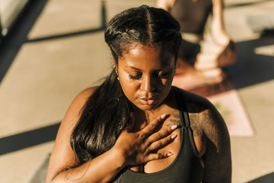 Plus size woman with hand on chest practicing breathing exercise at retreat center