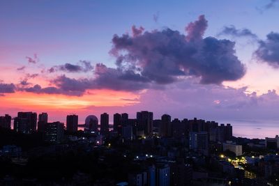 Illuminated buildings in city against sky during sunset