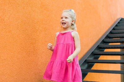 Portrait of young woman standing against wall