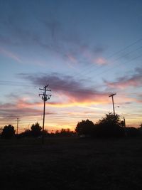 Low angle view of silhouette electricity pylon on field against sky