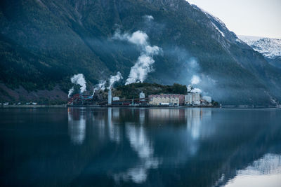 Factory by lake and mountain