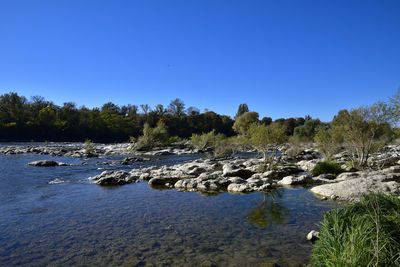 Scenic view of waterfall against clear blue sky