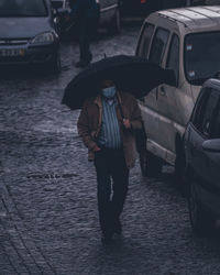 Man with umbrella walking on street in rainy season