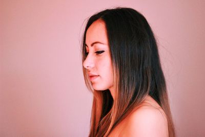 Close-up portrait of young woman against gray background