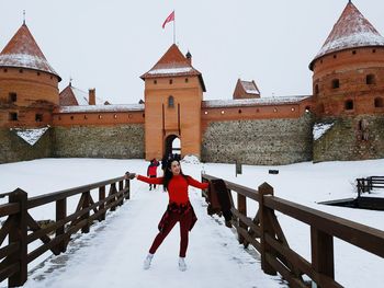Full length of woman standing by railing against castle during winter