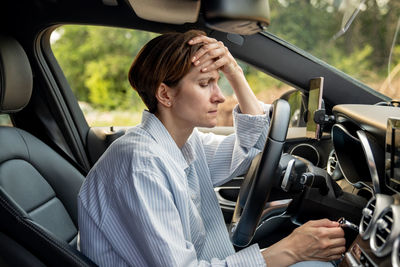 Side view of young woman sitting in car