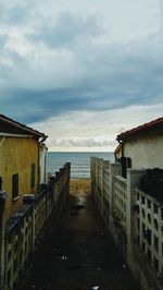 Walkway amidst buildings and sea against sky