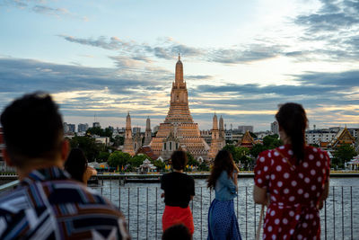 Rear view of people looking at temple against building