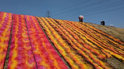 Low angle view of men drying laundry on land against clear sky