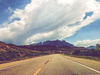 Road leading towards mountains against sky