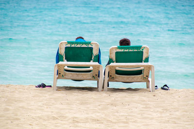 Rear view of people sitting on chair at beach