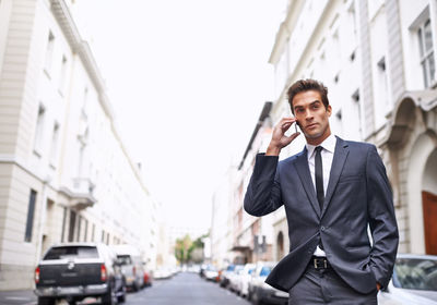 Portrait of businessman standing against buildings