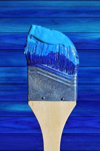 Close-up of paintbrush against blue wall