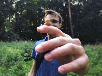 Close-up of man holding frog in forest