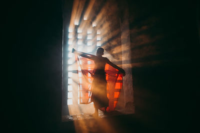 Silhouette man standing in illuminated building