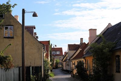 Street amidst houses and buildings in town against sky