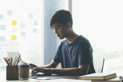 Young man using mobile phone while sitting on table