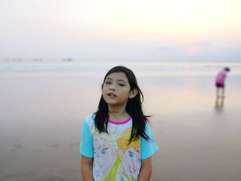 Portrait of girl standing at beach against sky