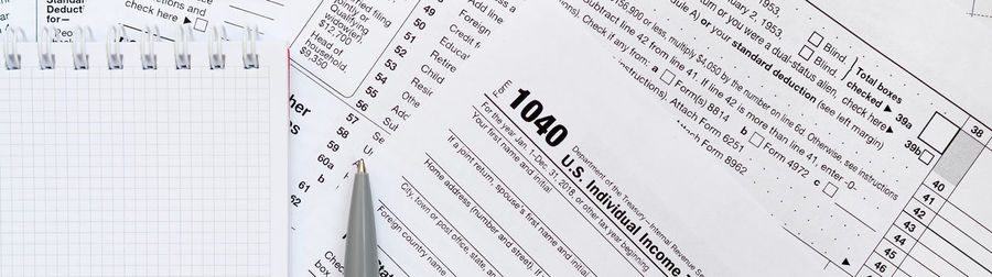 Panoramic view of tax forms with pen and notebook