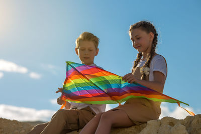 Teenage friends met in nature, talking and collecting kite.