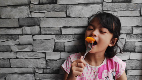 Portrait of a happy little girl eating mango at home