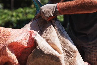 Midsection of man with plastic sack at tree plantation