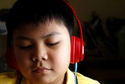 Close-up of boy listening music on headphones against black background