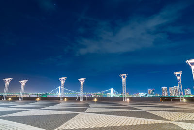 Illuminated bridge against blue sky at night