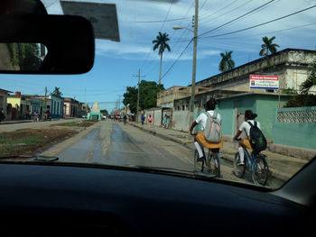 People riding motorcycle on street seen through car windshield