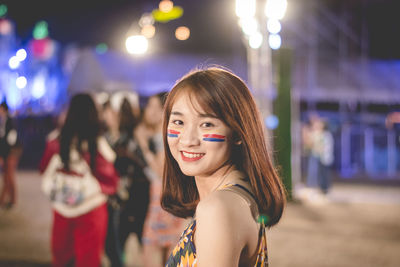 Portrait of smiling young woman standing outdoors at night