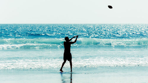 Full length of man with arms raised on beach against sky