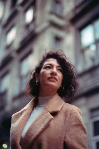 Low angle view of woman looking away while standing against building