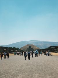 Group of people on landscape against clear blue sky