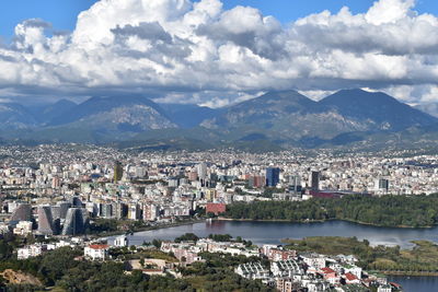 Aerial view of townscape by mountains against sky