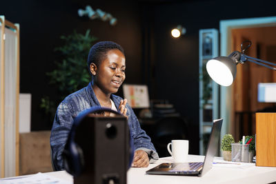 Portrait of young woman using mobile phone while sitting on table