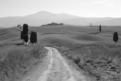Dirt road on field against sky