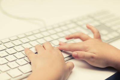 Close-up of kid typing on computer keyboard.