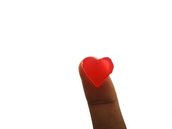 Close-up of hand holding heart shape over white background