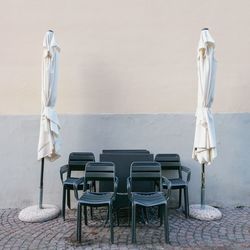 Empty chairs and table against wall