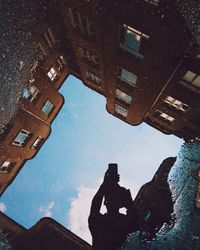 Low angle view of buildings against sky in puddle