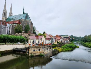 Buildings by river against sky