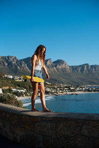 Full length of woman standing on mountain against clear blue sky