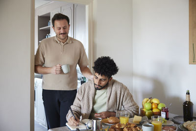Happy gay couple eating breakfast at home