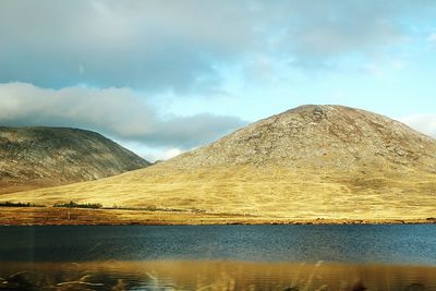 Scenic view of lake by mountain against sky