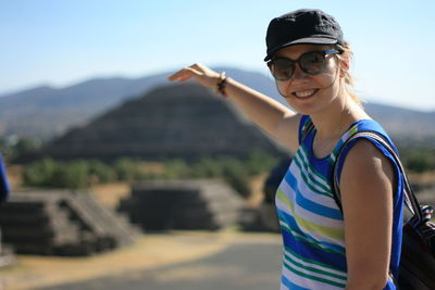 Optical illusion of cheerful woman touching pyramid