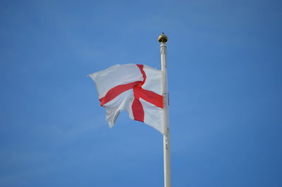 Low angle view of english flag waving against blue sky