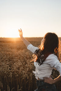 Woman standing on field against sky during sunset