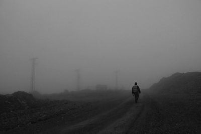 Rear view of person walking on road against sky