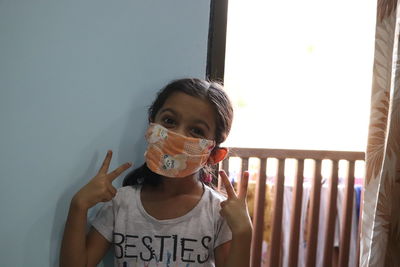 Smiling little girl wearing pollution mask and showing victory sign